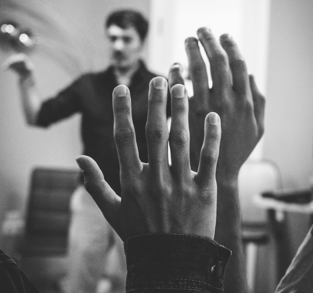 grayscale photography of two people raising their hands