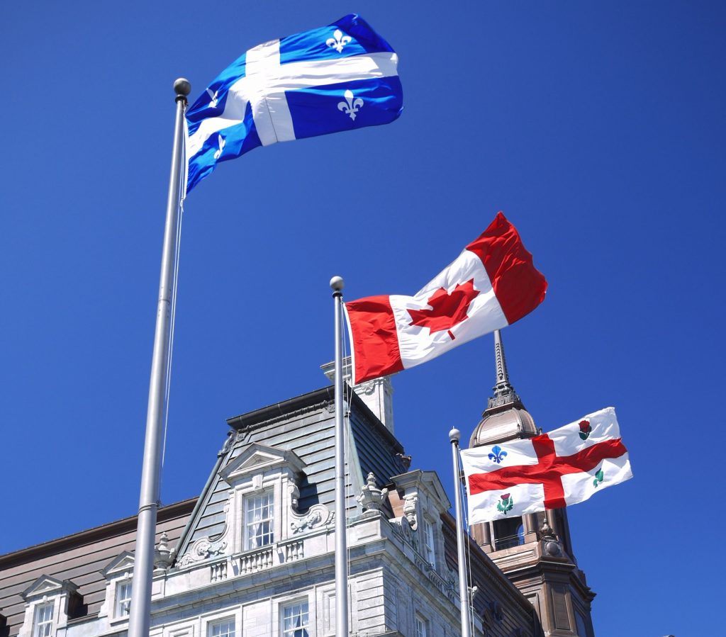 Flags of Québec, Canada and Montréal against blue sky